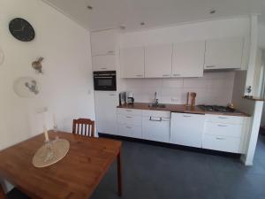 弗劳温普尔德Appartement Boomgaard的厨房配有白色橱柜和木桌