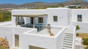 德里奥斯Hercules house pyrgaki paros的白色的房子,旁边设有白色的楼梯和桌子