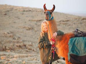 米茨佩·拉蒙Alpaca Farm - חוות האלפקות的站在小骆驼旁边的女人