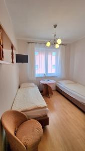 米泽德沃兹Pokoje Arka的一间卧室设有两张床、一把椅子和一个窗户。