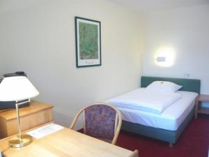 慕尼黑英格里申伽藤贝德斯汀酒店的一间卧室配有一张床和一张带台灯的书桌