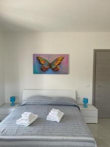 托尔托拉B&B Il Dolce Nido的一间卧室配有一张床上,墙上挂着蝴蝶画