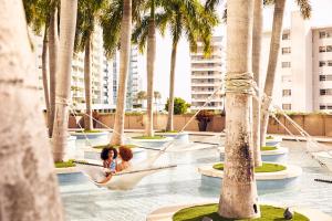 迈阿密迈阿密四季酒店的棕榈树泳池吊床上的女人