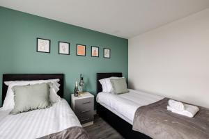 曼彻斯特Stunning 2 bed apt with free parking close to CC的蓝色墙壁客房的两张床