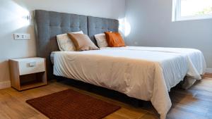 桑提亚纳德玛Natura Cantabria的卧室配有一张带白色床单和枕头的大床。