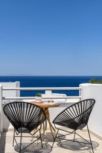 米克诺斯城Casa Anna Suites的阳台配有一张桌子和两把椅子,享有海景
