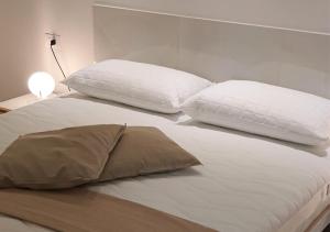 蒙特西尔瓦诺Elegante appartamento a due passi dal mare的一张带两个枕头和一盏灯的白色床
