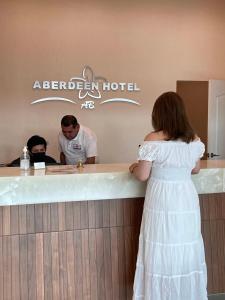 多洛雷斯-伊达尔戈ABERDEEN HOTEL DOLORES HIDALGO的站在酒吧的身着白色衣服的女人