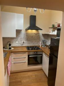 热那亚Il Nido Del Borgo的厨房配有白色橱柜和黑炉灶烤箱。
