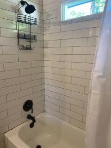 士麦那Cozy 2-bedroom Farmhouse with parking on premise的白色瓷砖浴室设有浴缸和窗户。