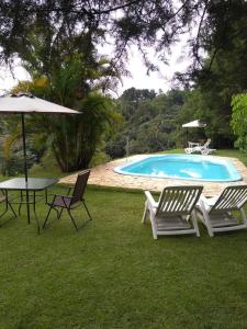 坎普林普Recanto Pôr do Sol的一个带两把椅子和一张桌子的游泳池以及一把遮阳伞
