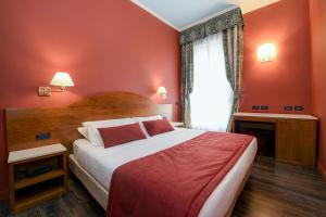 代森扎诺-德尔加达城市酒店的一间卧室设有一张红色墙壁和窗户的床