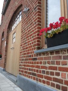 ZandvoordeKunstmin的砖砌的建筑,有门,窗户上有鲜花