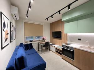 地拉那Dolce far niente Apartment的一间带蓝色沙发的客厅和一间厨房