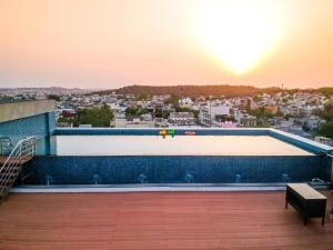 博帕尔Radisson Bhopal的一座享有日落美景的建筑屋顶上的游泳池