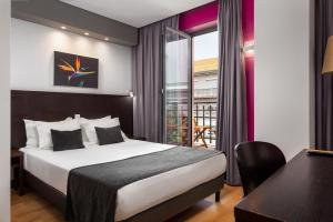 里斯本卢埃纳酒店的配有一张床、一张书桌和一扇窗户的酒店客房