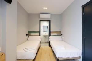 塞丹约拉·德尔·瓦勒Hey Rooms的配有2张床的白色墙壁和镜子
