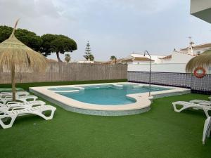 马塔拉斯卡尼亚斯Apartamentos Costa Luz的一个带两把草坪椅和遮阳伞的游泳池