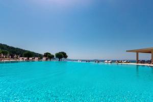 尼基季Ammoa Luxury Hotel & Spa Resort的蓝色海水和海滩的大型游泳池
