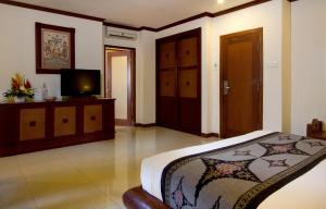 塞米亚克Balisani Suites Hotel的一间卧室配有一张床和一台平面电视