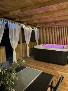 塞尔瑟Rosmarin&Olive Premium Mobile Homes的木甲板上的按摩浴缸,配有窗帘