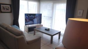 布列登Blutsyde Promenade Encanto的带沙发、电视和桌子的客厅