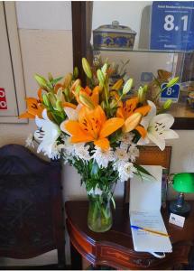 科英布拉阿连特亚纳住宅酒店的花瓶,上面摆放着橙色和白色的花朵