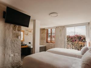 阿雷基帕La Hostería Boutique Hotel的一间卧室设有两张床,墙上配有电视。