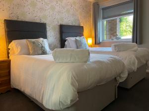 伍德哈尔温泉水疗Village Limits Bed and Breakfast Rooms的一间卧室设有两张带白色床单的床和窗户。