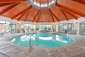 佩科斯瑞士木屋贝斯特韦斯特优质套房酒店的大型室内游泳池设有木制天花板和窗户