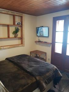 蒙特韦尔迪Recanto das Glicínias的卧室配有一张床,墙上配有电视。