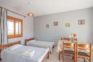 Ágios NikólaosPine tree Apartment & sunset的一间设有两张床和一张桌子及椅子的房间
