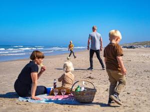 布洛克胡斯4 person holiday home on a holiday park in Blokhus的一群儿童在海滩上玩耍