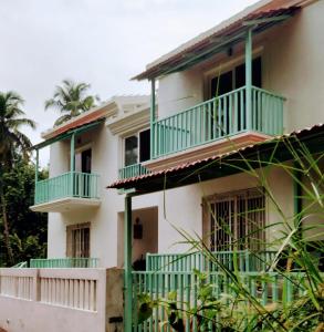 比纳里姆Beseco Bed and Breakfast的白色的房子,设有绿色的阳台和棕榈树