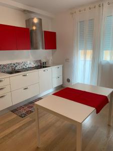 帕多瓦Appartamenti Scrovegni的厨房配有红色橱柜和红色地毯的桌子