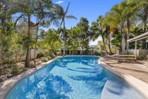努萨维尔Stylish Townhouse, private courtyard walk to beach的棕榈树庭院里的一个蓝色海水游泳池