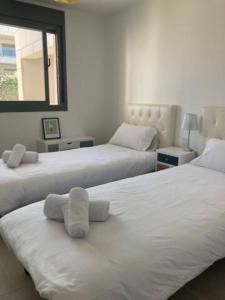 EsteponaAppartement Casares - Mer, Golf, Piscine, Padel - FINCA CORTESIN的一间卧室配有两张带毛巾的床