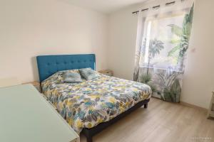 巴登LES 7 ÎLES的一间卧室配有一张带蓝色床头板的床和窗户