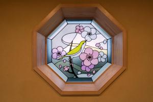 京都Kyoto Umekoji Kadensho的鸟坐在鲜花枝上的彩色玻璃窗