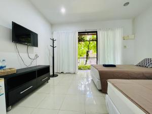 Ban Na PhoWassana Sitdharma Guesthouse的酒店客房设有两张床、一台电视和一台电视机。