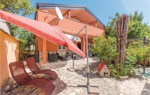 沃希Cozy Home In Vrsi With Wifi的庭院配有两把椅子和一把红色遮阳伞