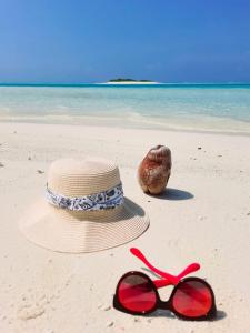 马提威力Mystic Maldives Mathiveri Retreat的沙滩上的草帽和红太阳镜