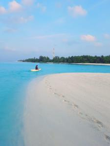 马提威力Mystic Maldives Mathiveri Retreat的坐在海滩冲浪板上的人