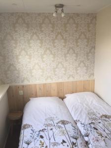 登霍伦Texelstrand的一间卧室配有一张床,墙上贴有壁纸