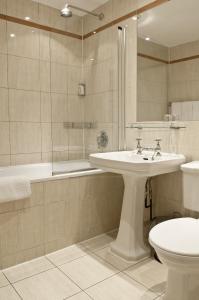 伦敦拉什莫尔酒店的一间带水槽、浴缸和卫生间的浴室