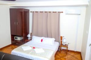 维多利亚Will's Sea View Apartments的一间卧室配有一张带白色床单和窗帘的床