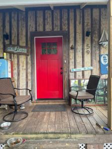圣奥古斯丁150 year old Restored Lincolnville cottage的木甲板上的红色门,配有两把椅子