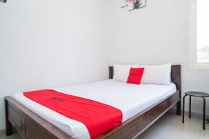 GununganjarRedDoorz Plus At Merr Rungkut Jl Gunung Anyar的一间卧室配有一张床铺,床上铺有红色毯子