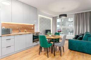 弗罗茨瓦夫Star4You II Apartments的厨房以及带桌子和绿色椅子的客厅。