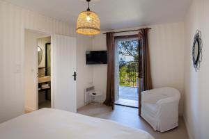 利勒鲁斯Villa bodri, maison en pierre avec vue mer et piscine chauffée的卧室配有白色的床和滑动玻璃门
